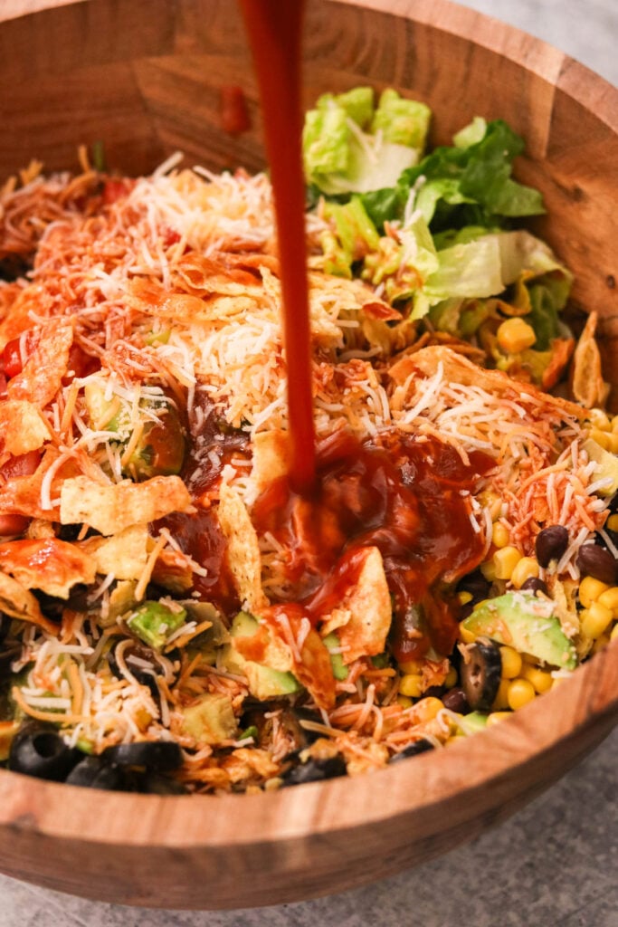 Close-up of pouring catalina dressing over the assembled taco salad.
