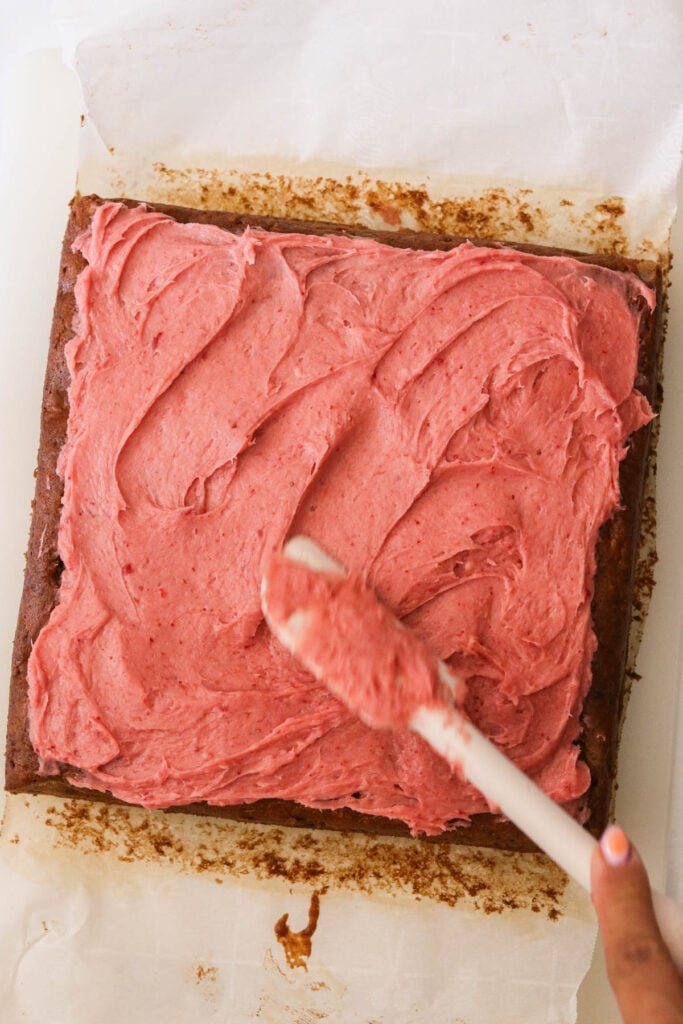 frosting the top of a strawberry banana cake. 