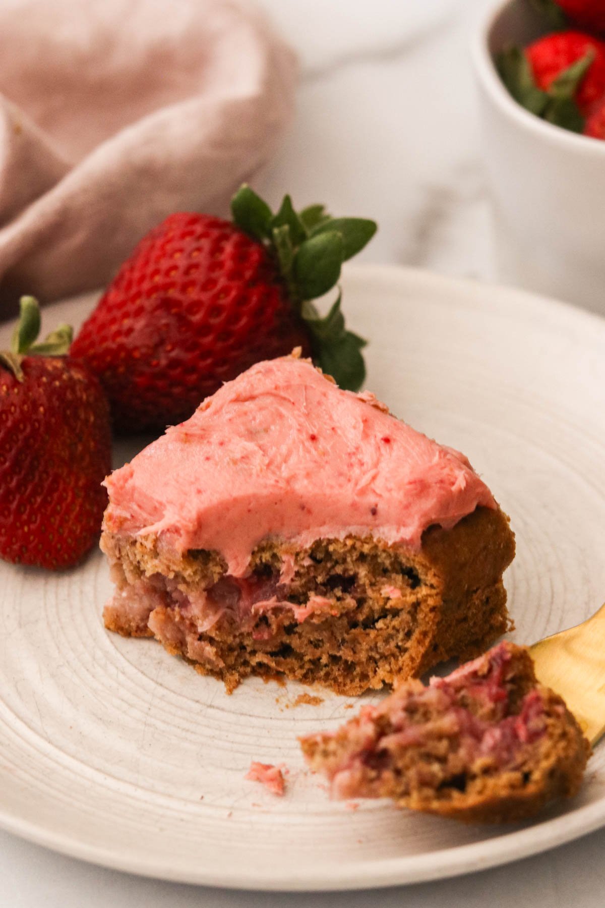 a strawberry banana cake square with a bite taken out. 