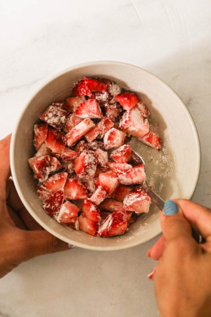 mixing chopped strawberries in flour 