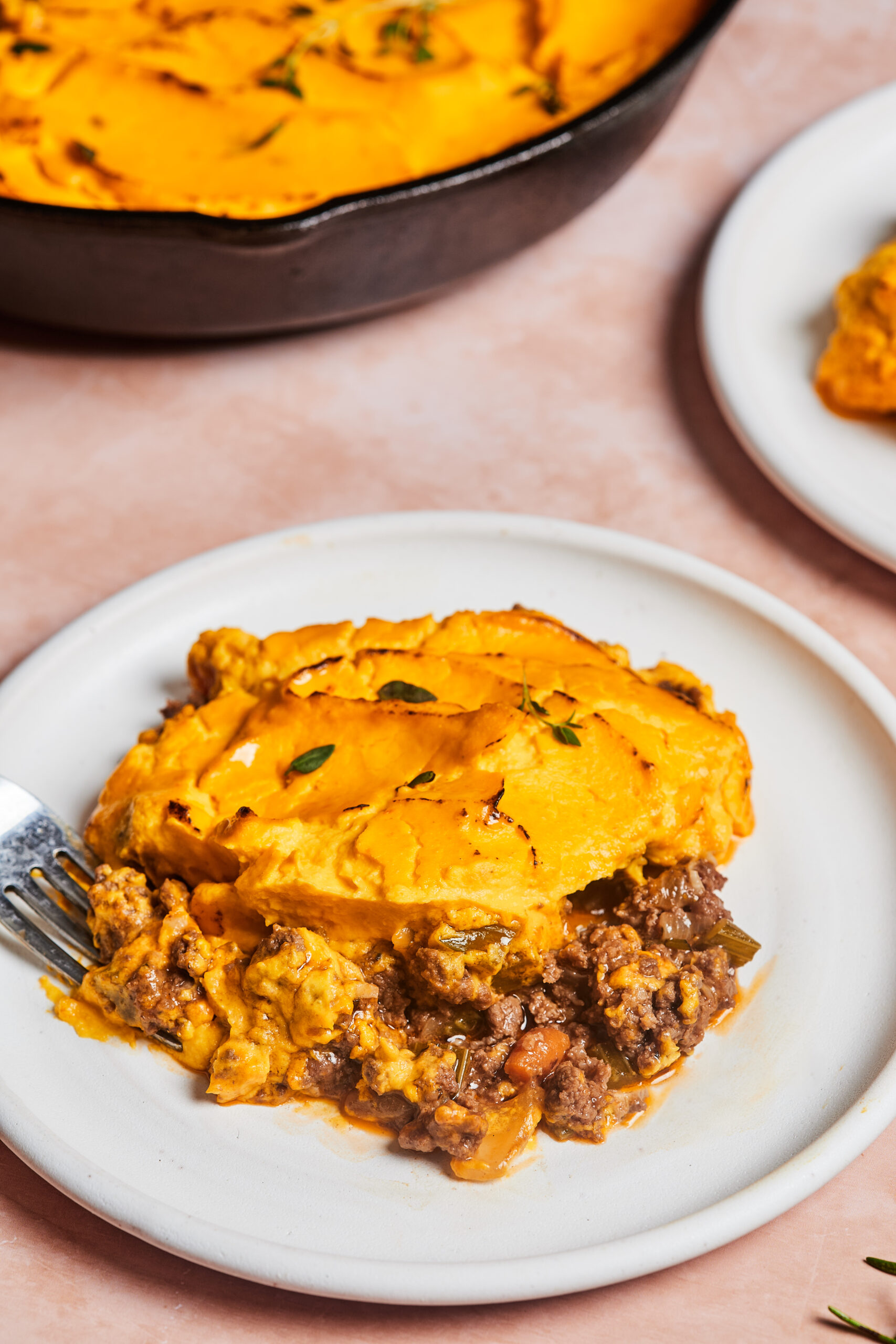 Low-carb shepherd’s pie served on a white plate with golden mash topping and meat filling spilling out the sides.