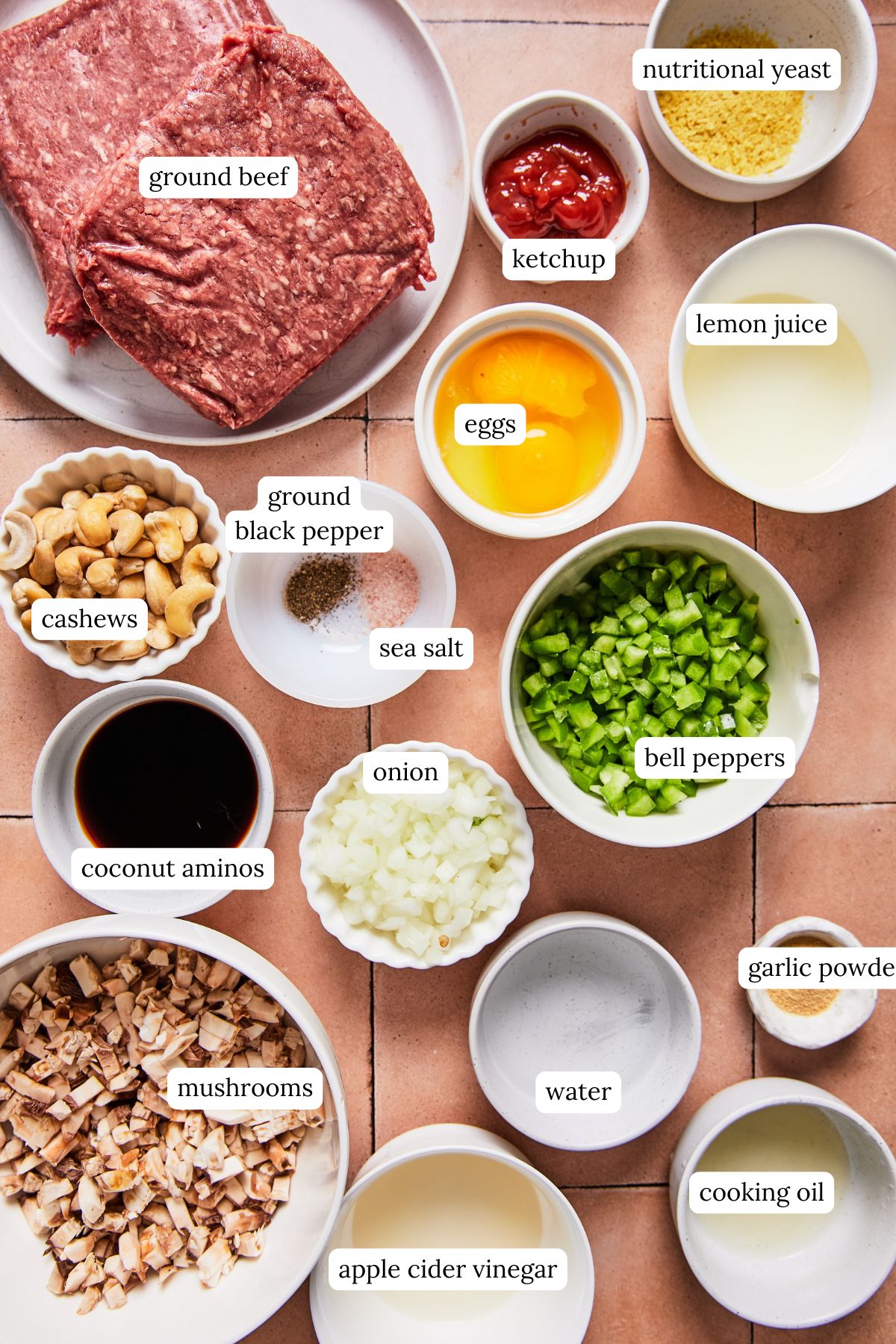 Ingredients for Philly cheesesteak meatloaf arranged in bowls, including ground beef, onion, green pepper, mushrooms, eggs, and cashews for cheese sauce.