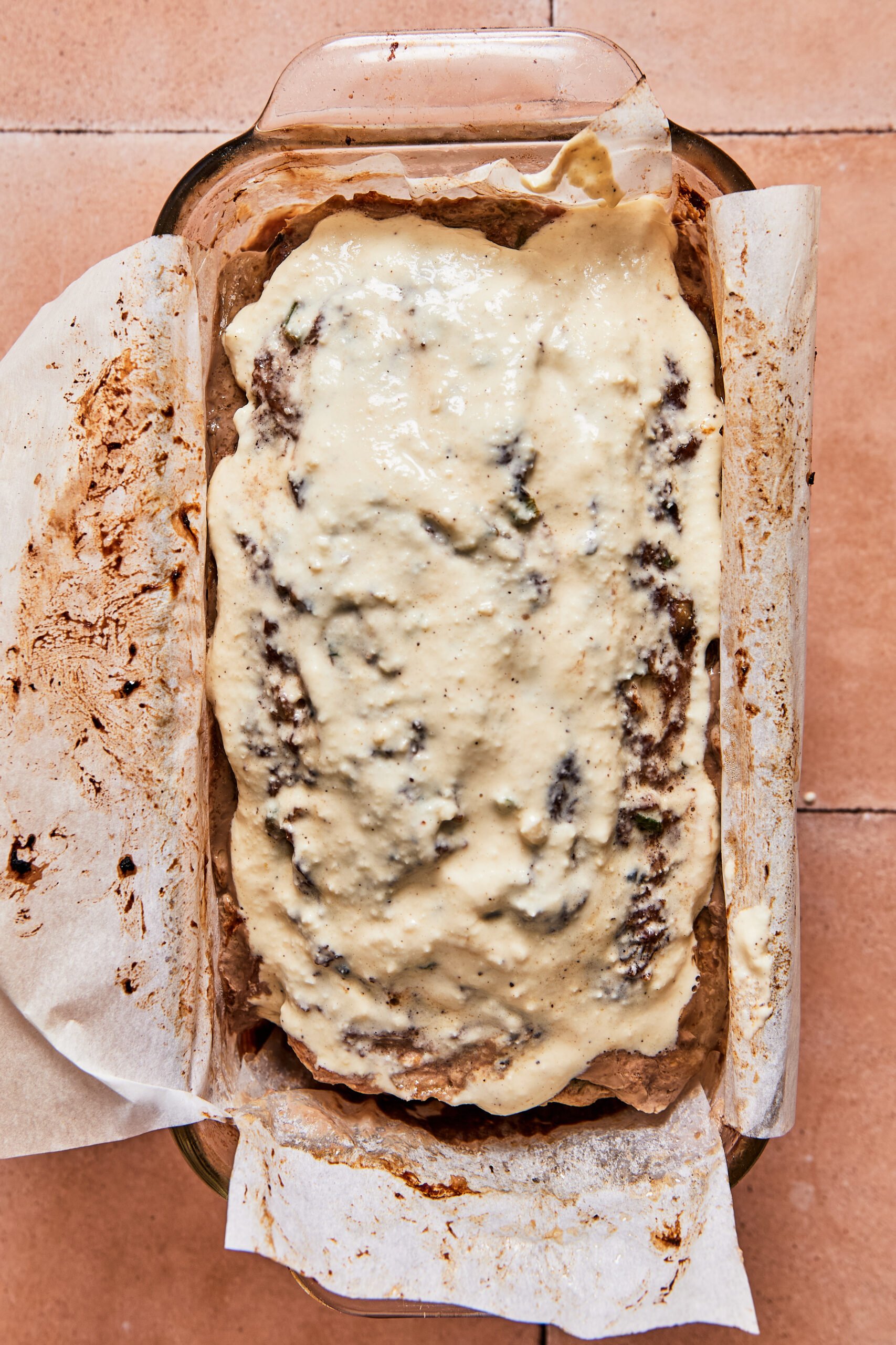 Philly cheesesteak meatloaf topped with blended cheese sauce, ready to go back in the oven.