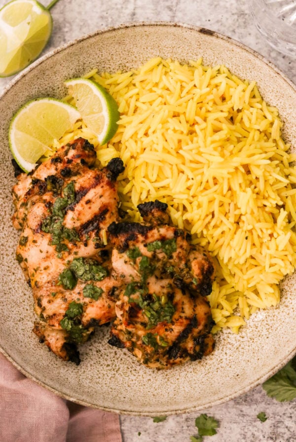 Grilled cilantro lime chicken thighs sliced on a platter with fresh lime wedges