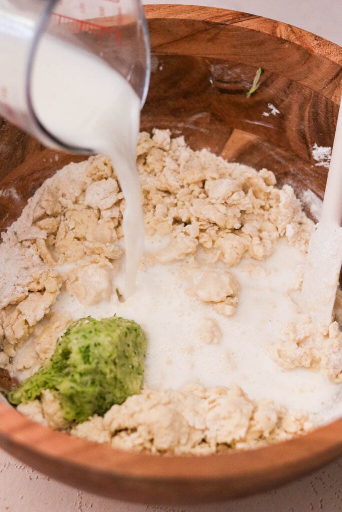 Milk being stirred into thick waffle batter in a mixing bowl 