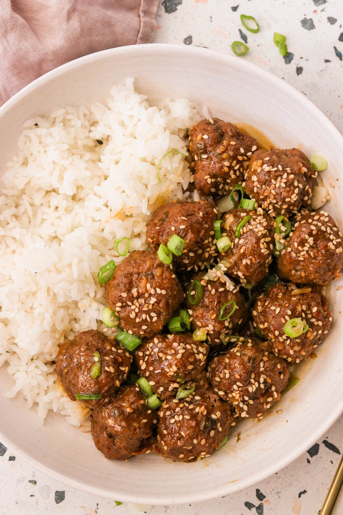 korean bbq meatballs garnished with green onions and sesame seeds on a plate with white rice