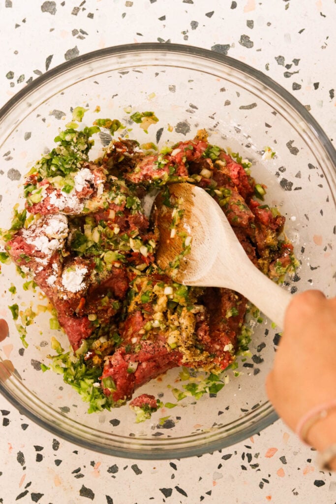 mixing meatball ingredients in a glass bowl
