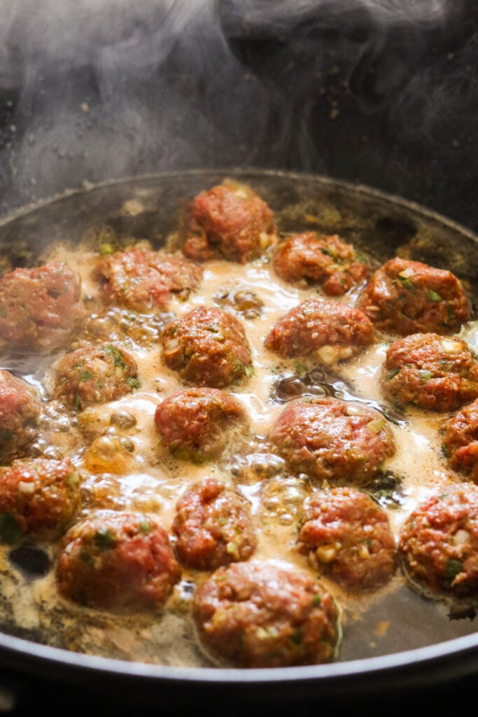 meatballs cooking in the skillet with the korean bbq sauce. 