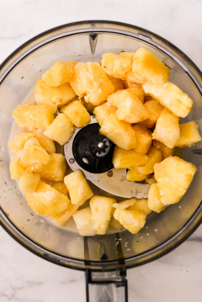 Ingredients added to food processor for blending pineapple Dole Whip