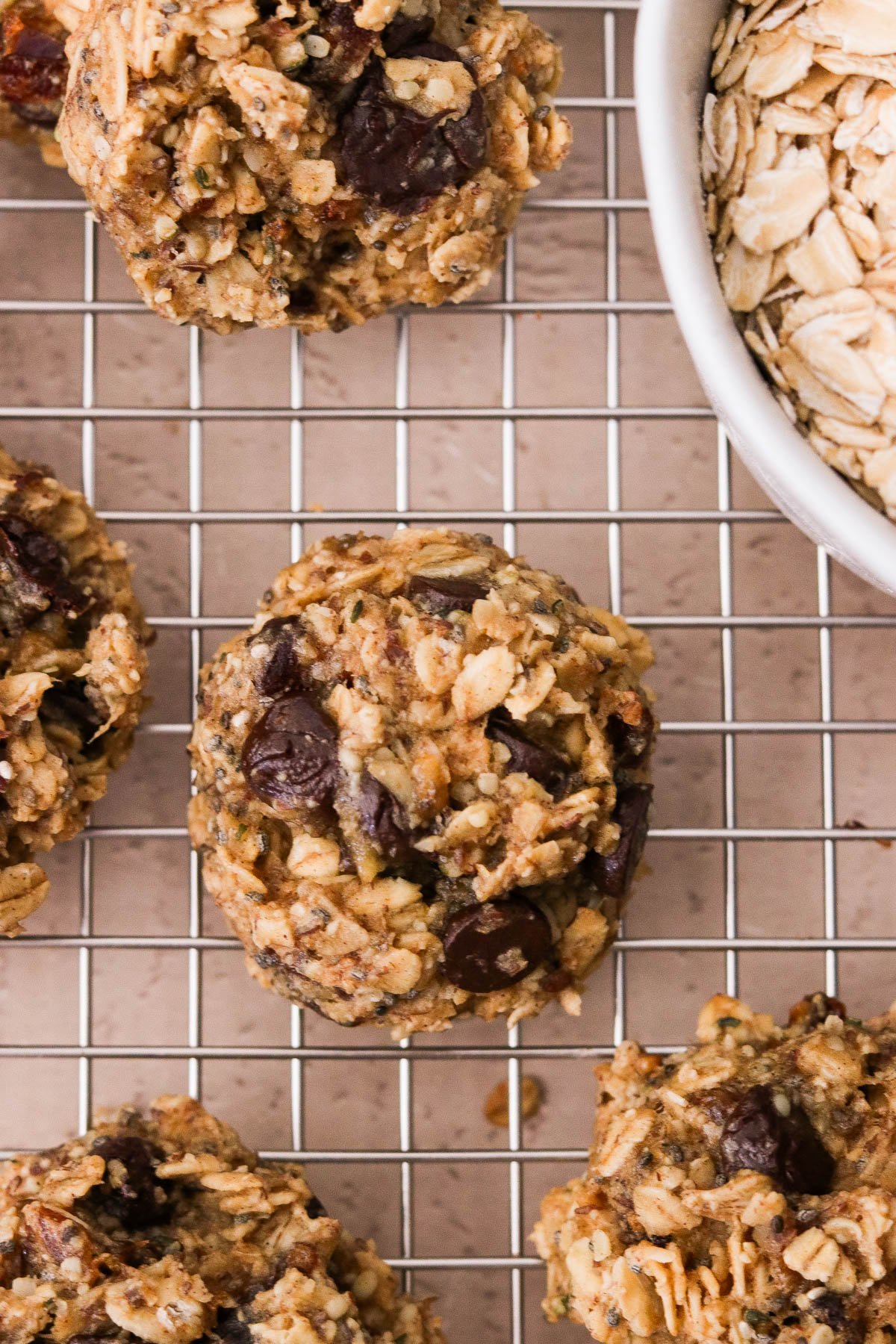 Close-up of breakfast oatmeal cookies on a wire rack with a light pink background.