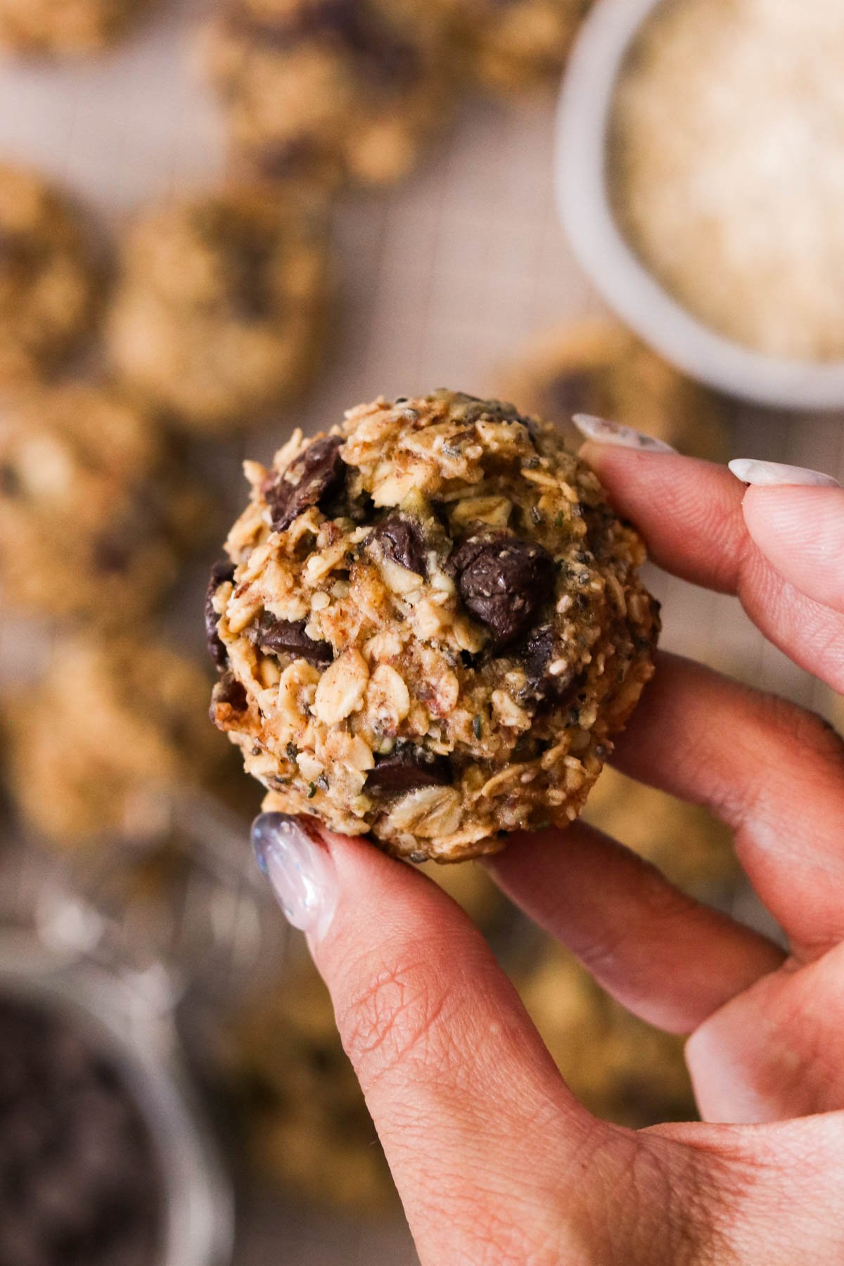 Fingertips holding a ball of breakfast oatmeal cookie dough.