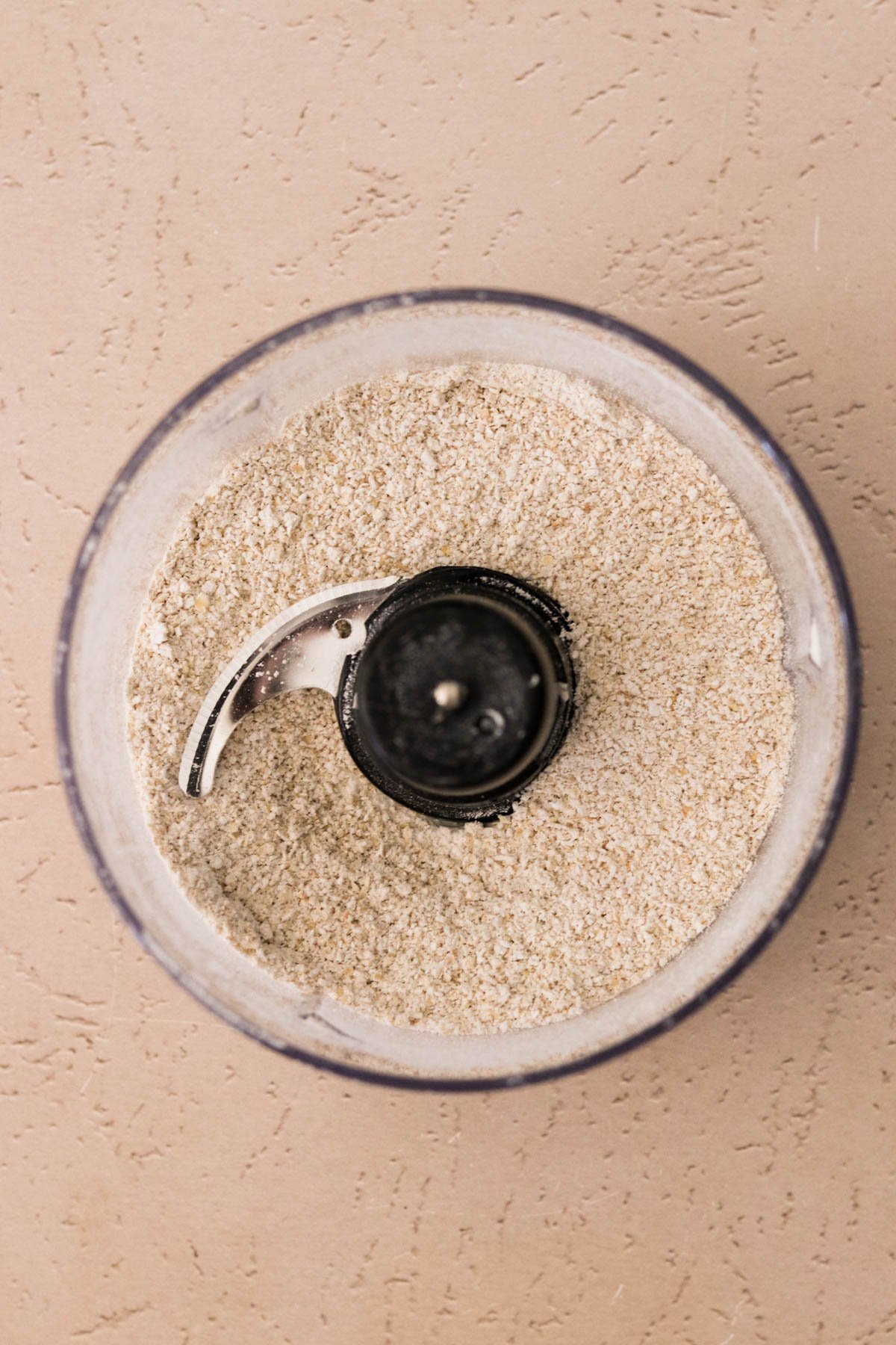 Food processor grinding rolled oats into fine oat flour.