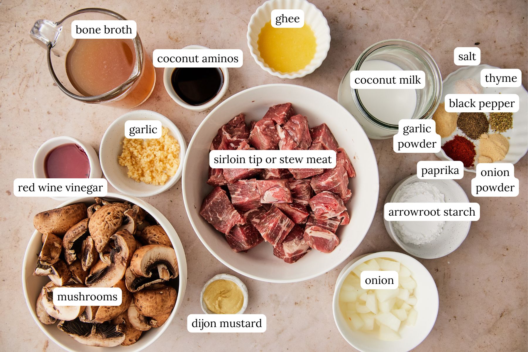 Measured ingredients for dairy-free beef stroganoff arranged on a counter, including beef, mushrooms, onions, spices, broth, coconut milk, and seasonings.