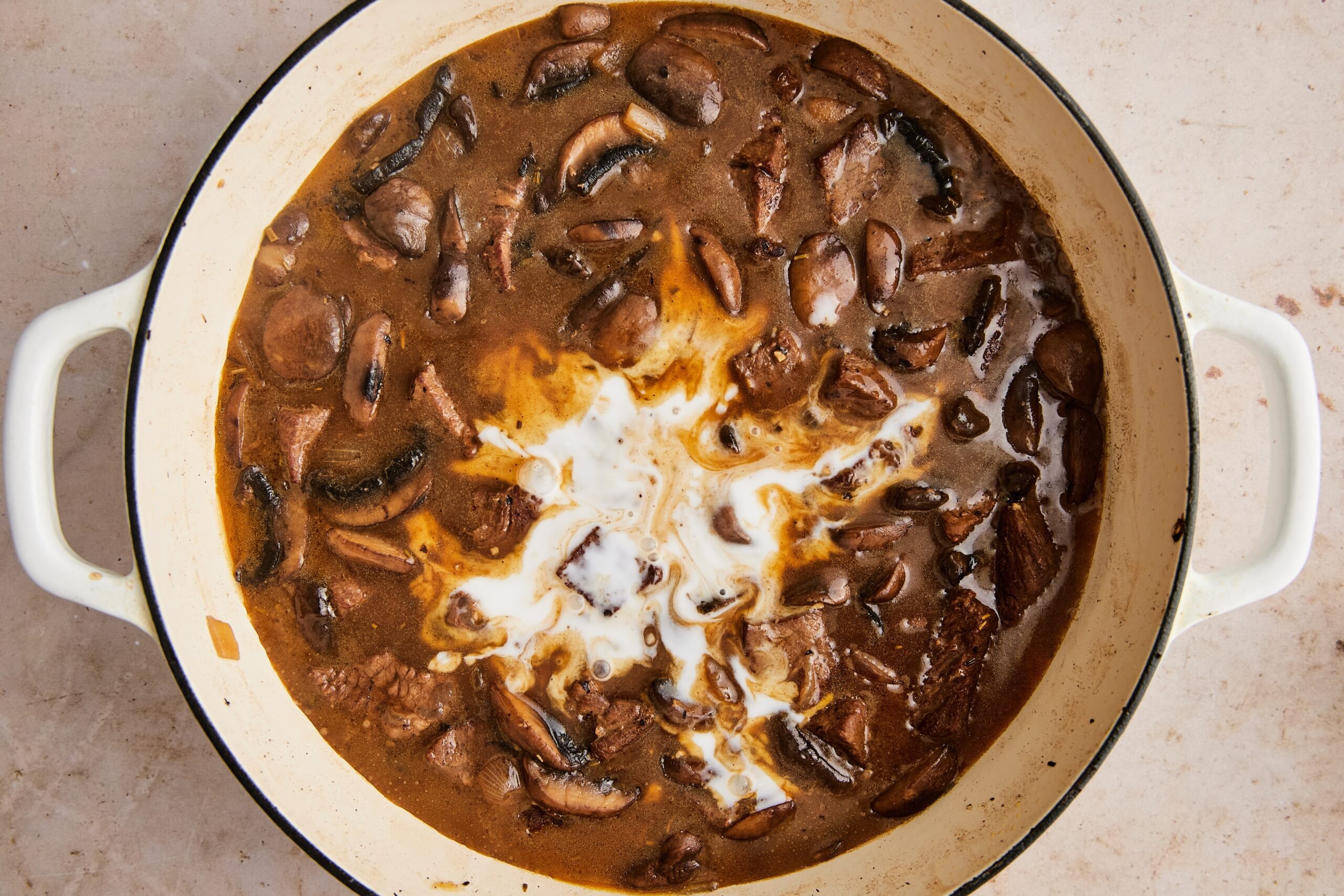 Stroganoff simmering in the pot with coconut milk stirred in, sauce thickening.