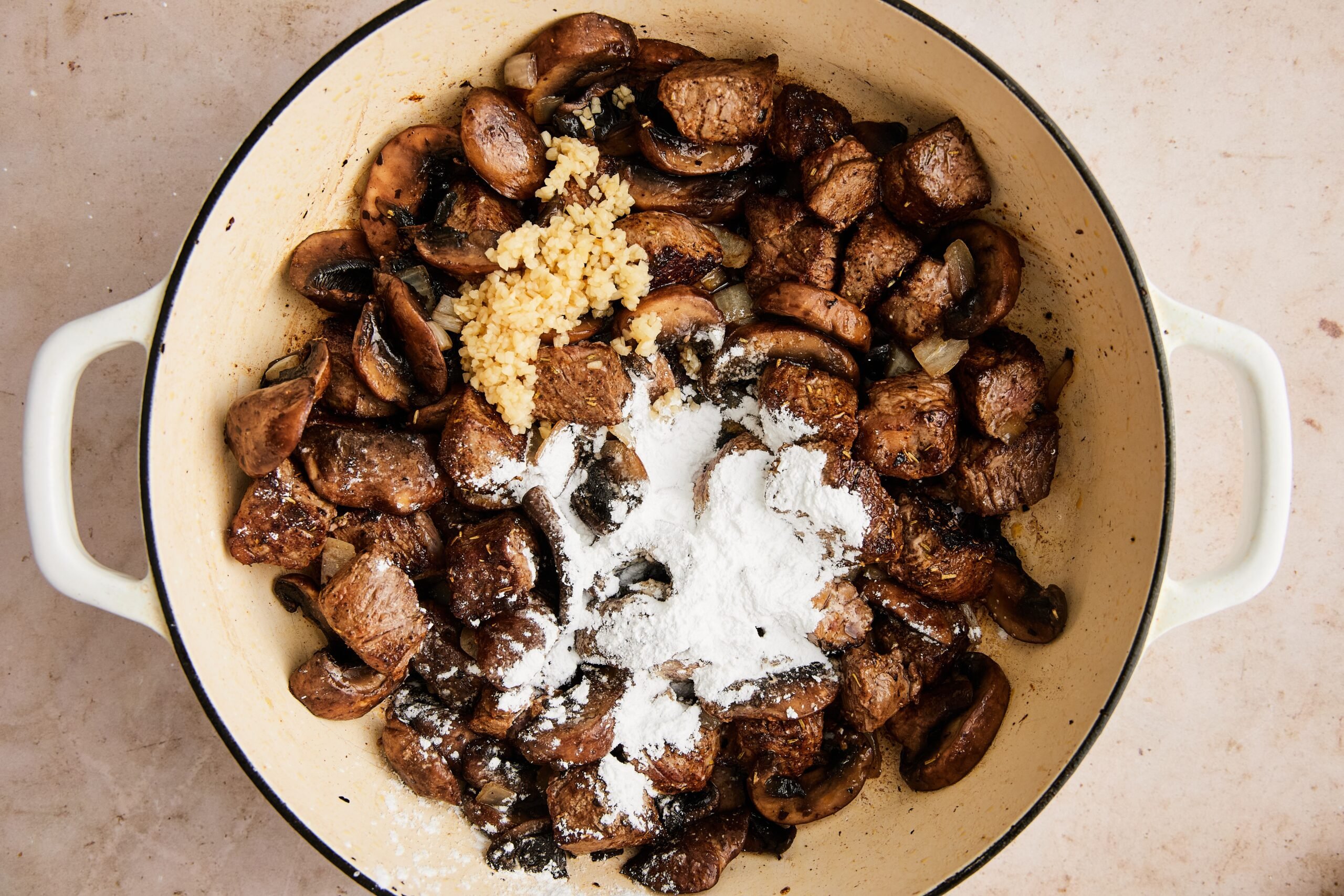 Garlic and arrowroot stirred into the pan, with broth, coconut aminos, vinegar, and Dijon added to build the sauce.