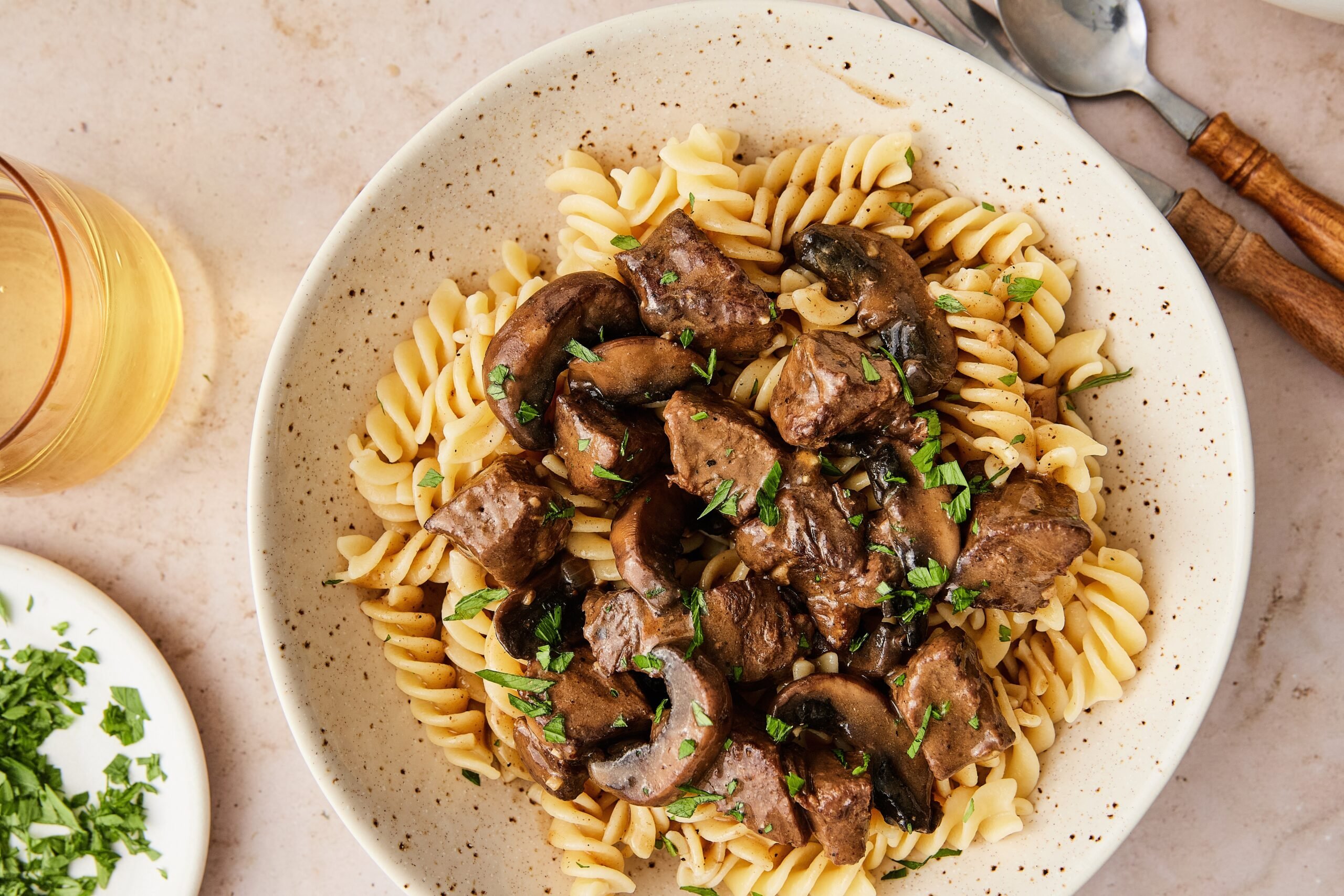 Dairy-free beef stroganoff served over gluten-free pasta, topped with fresh parsley.