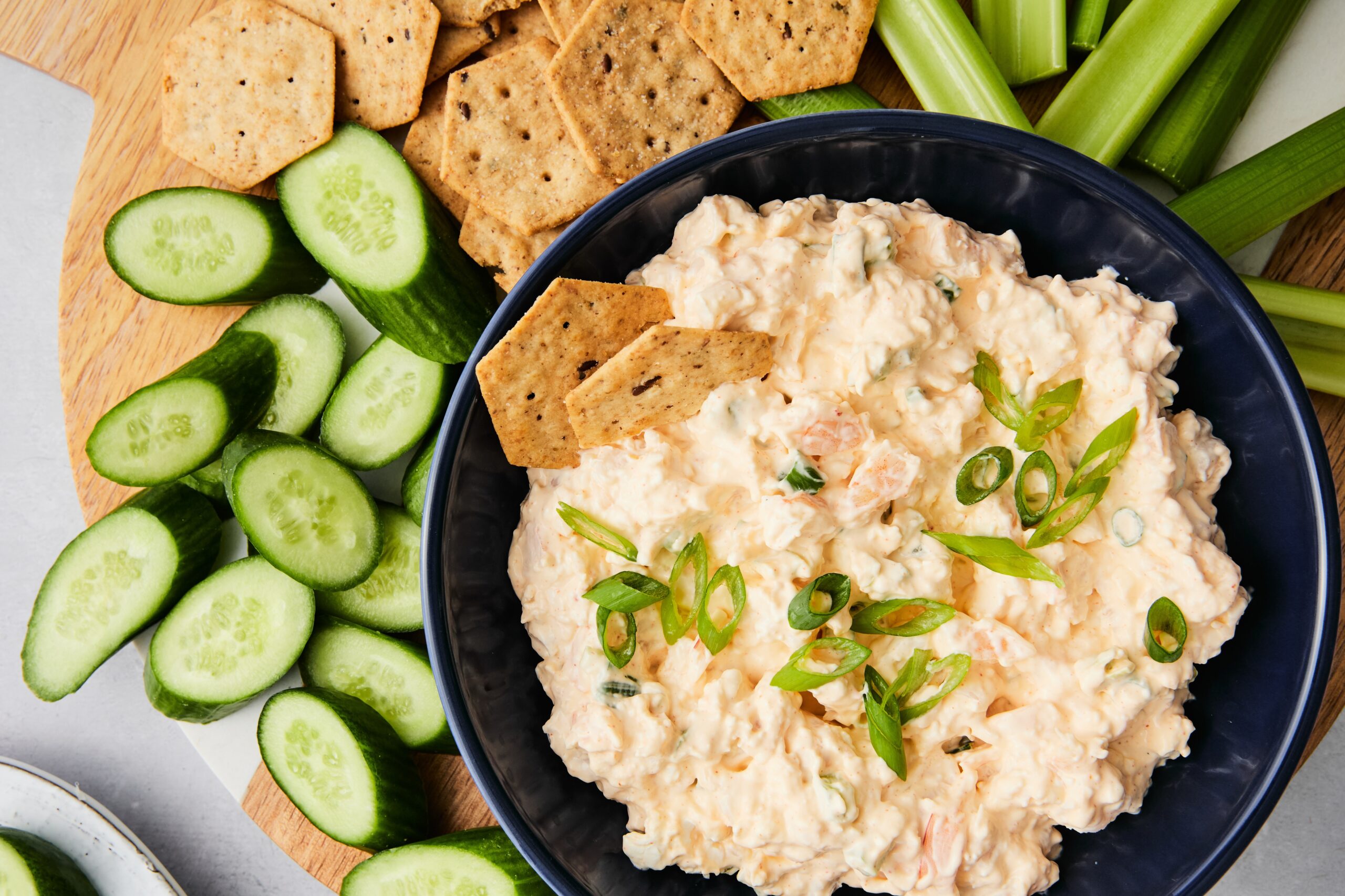Chilled shrimp dip in a serving bowl with crackers, chips, and fresh vegetables for dipping.