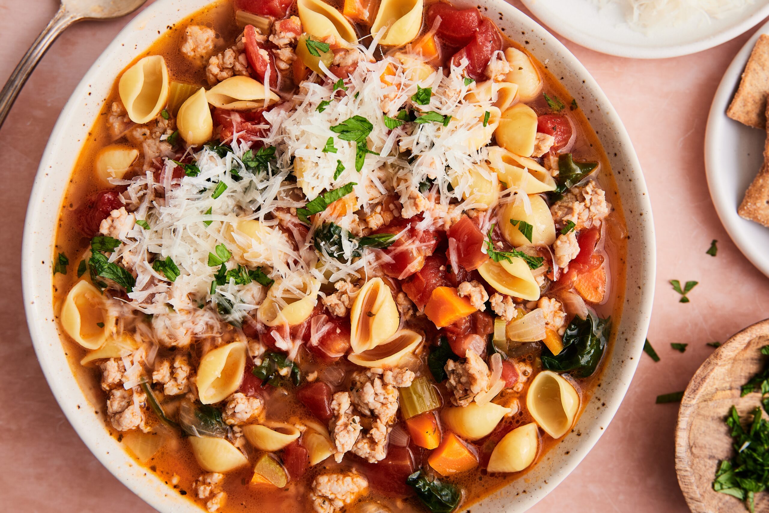Finished Italian sausage and pasta soup served hot in a bowl, garnished with parmesan cheese.