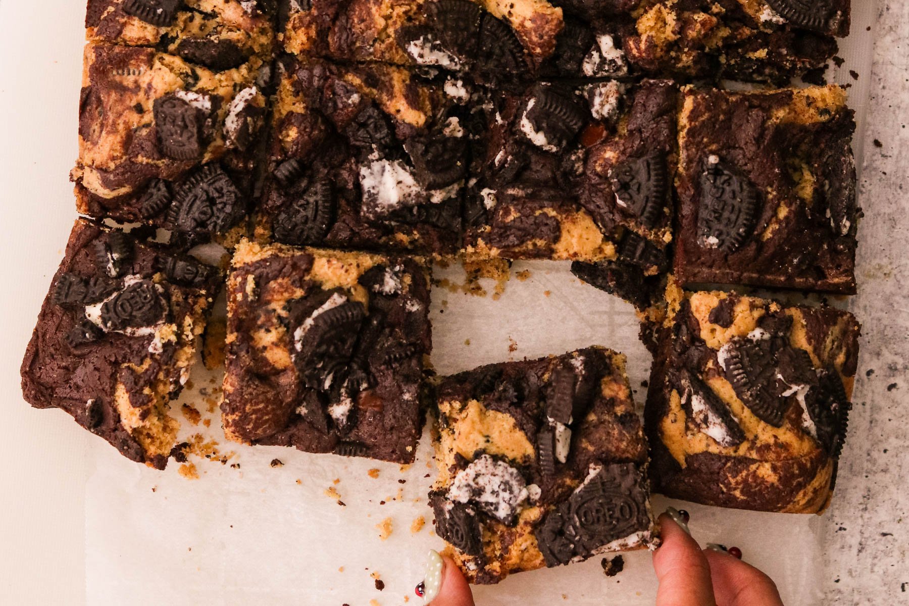 Cooled Oreo brookies cut into squares, with one piece being lifted to eat.