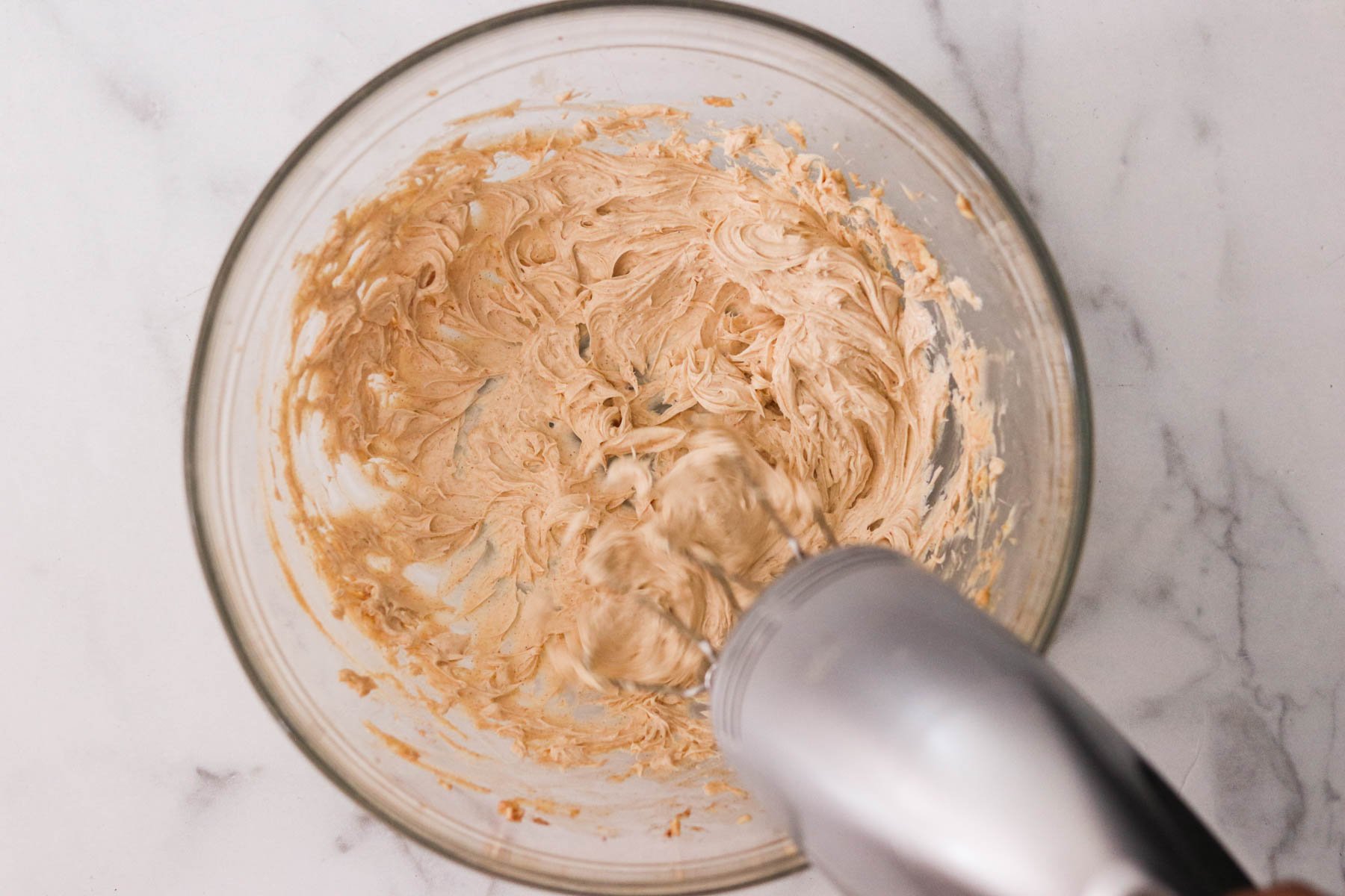 Cinnamon maple butter ingredients whipped together in a small glass bowl with a whisk.