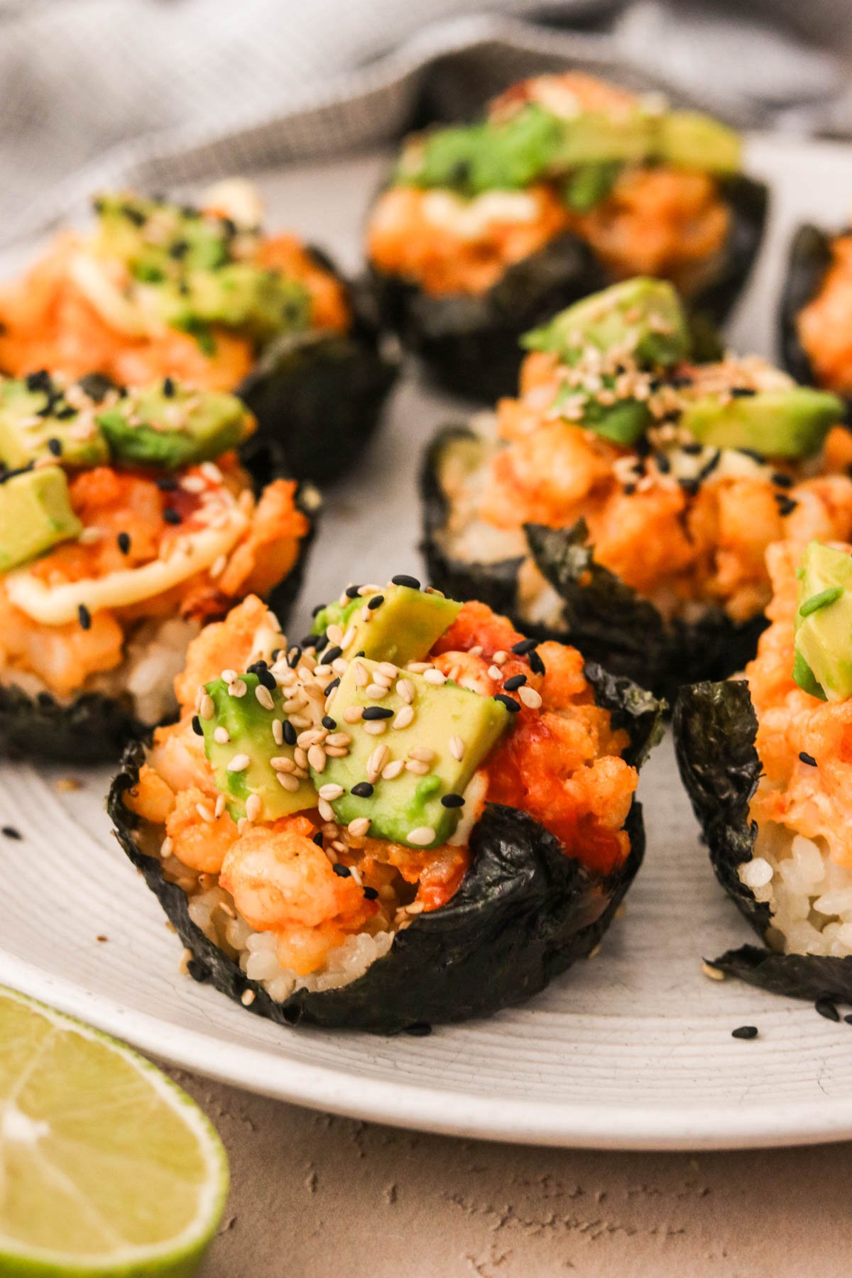 Close-up of shrimp sushi cups topped with avocado and sesame seeds served on a white dish.