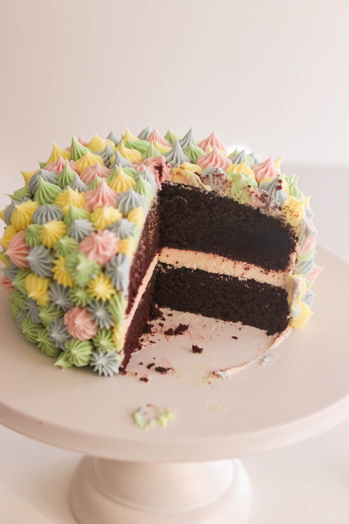 A gluten free chocolate cake 6-inch two-layer with rich buttercream frosting with a slice cut out on a cake stand