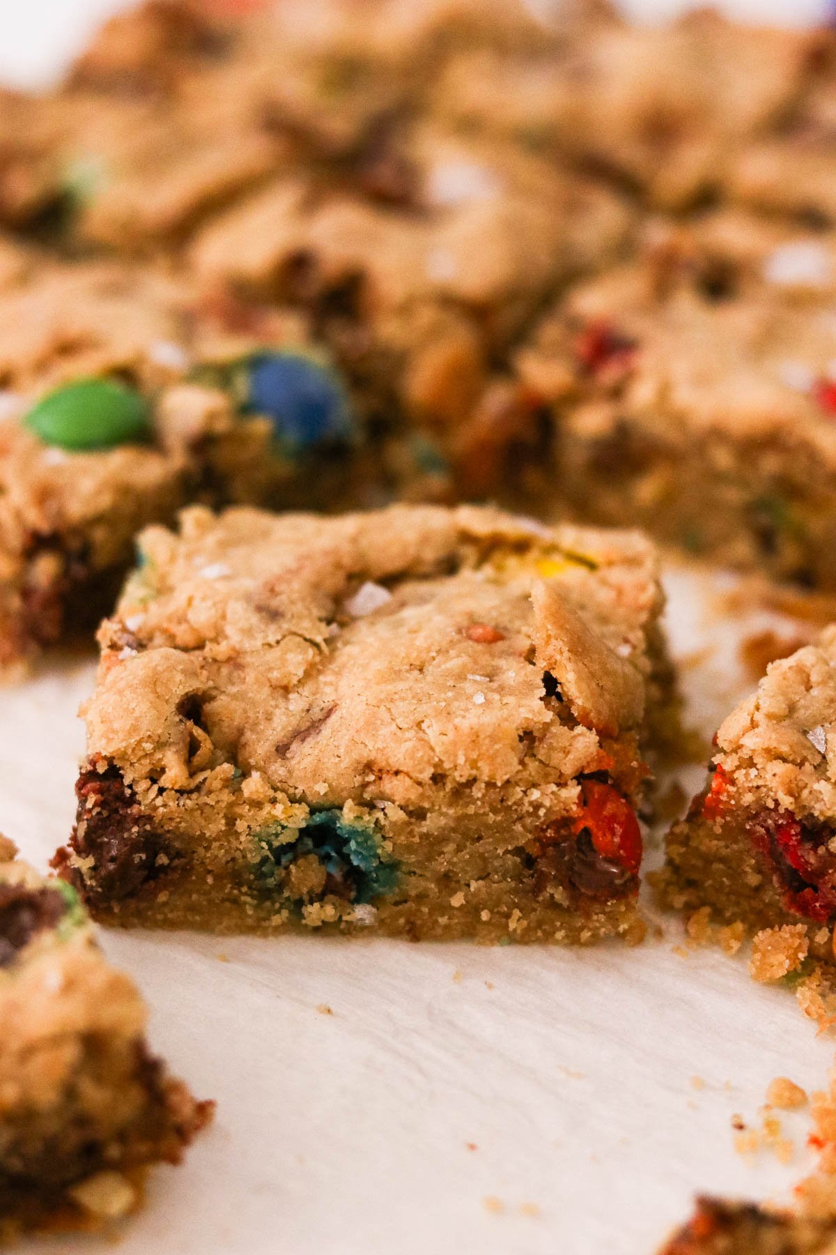 Close-up of a cut slice of a leftover halloween candy cookie bar garnished with flaky sea salt.