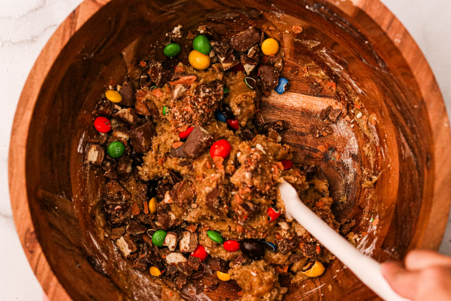 Ingredients for the shortbread layer being mixed in a large bowl, forming a dough.