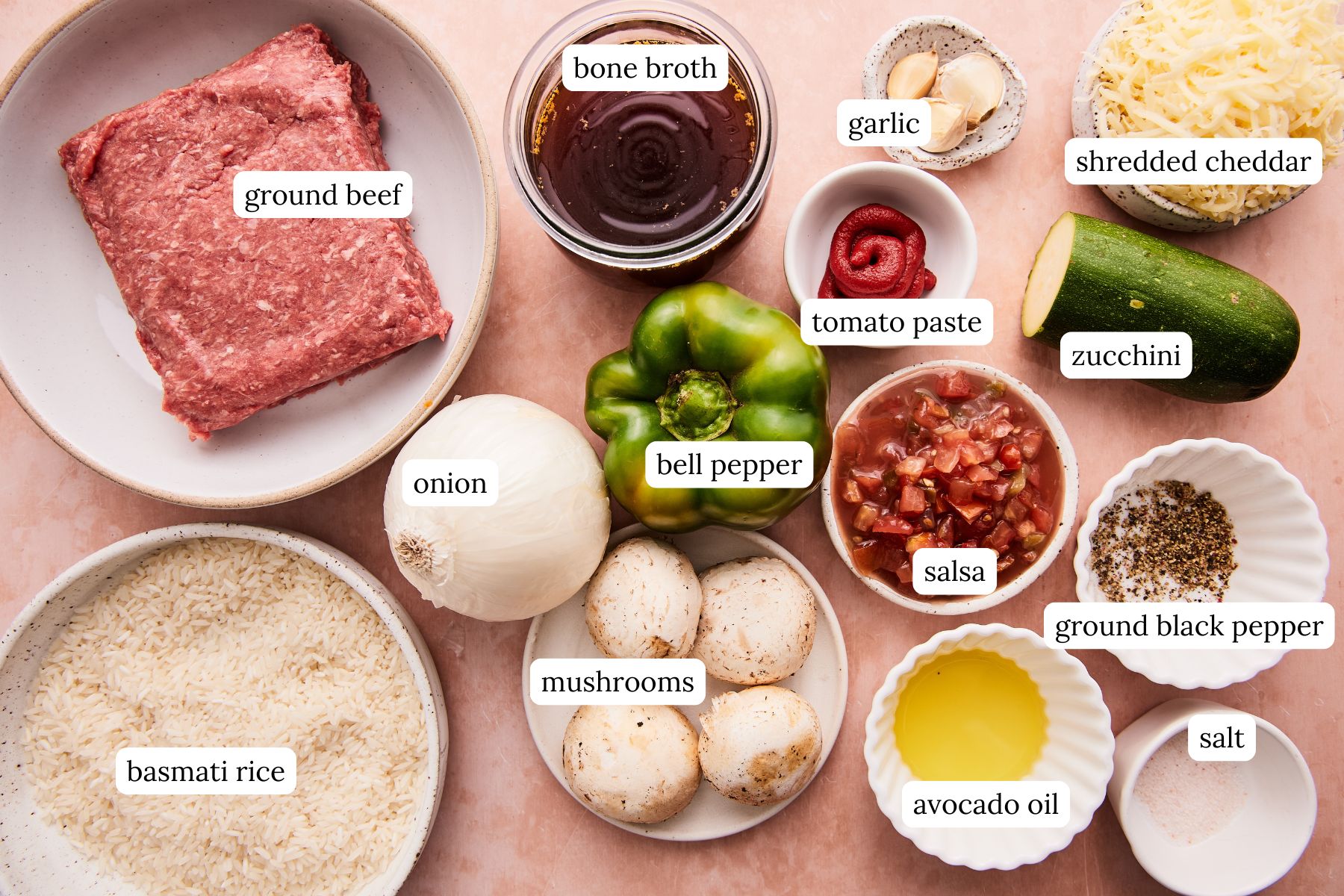 Ingredients for ground beef and rice skillet labeled and arranged on a pink counter top.
