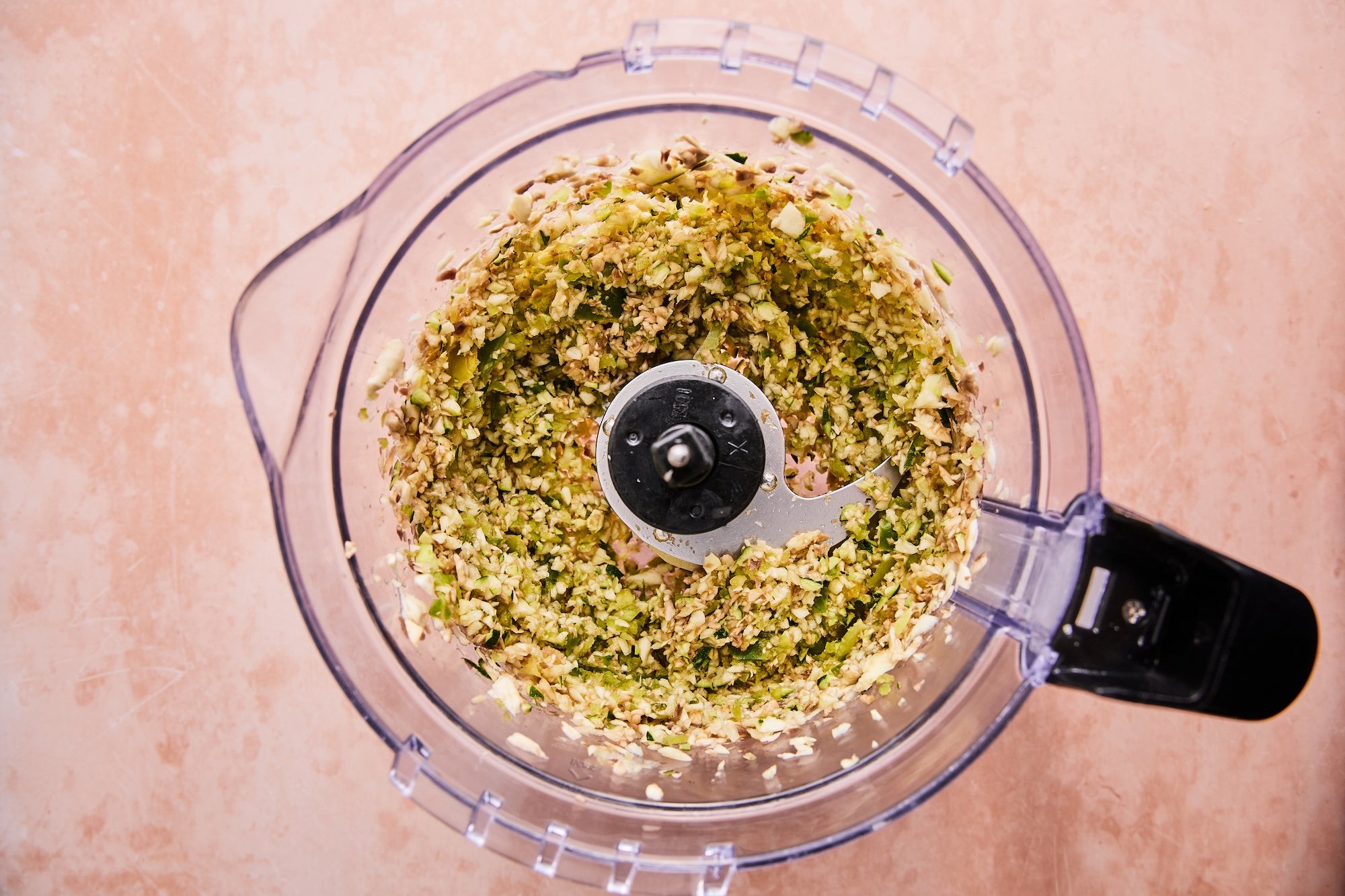 Food processor with chopped veggies inside.
