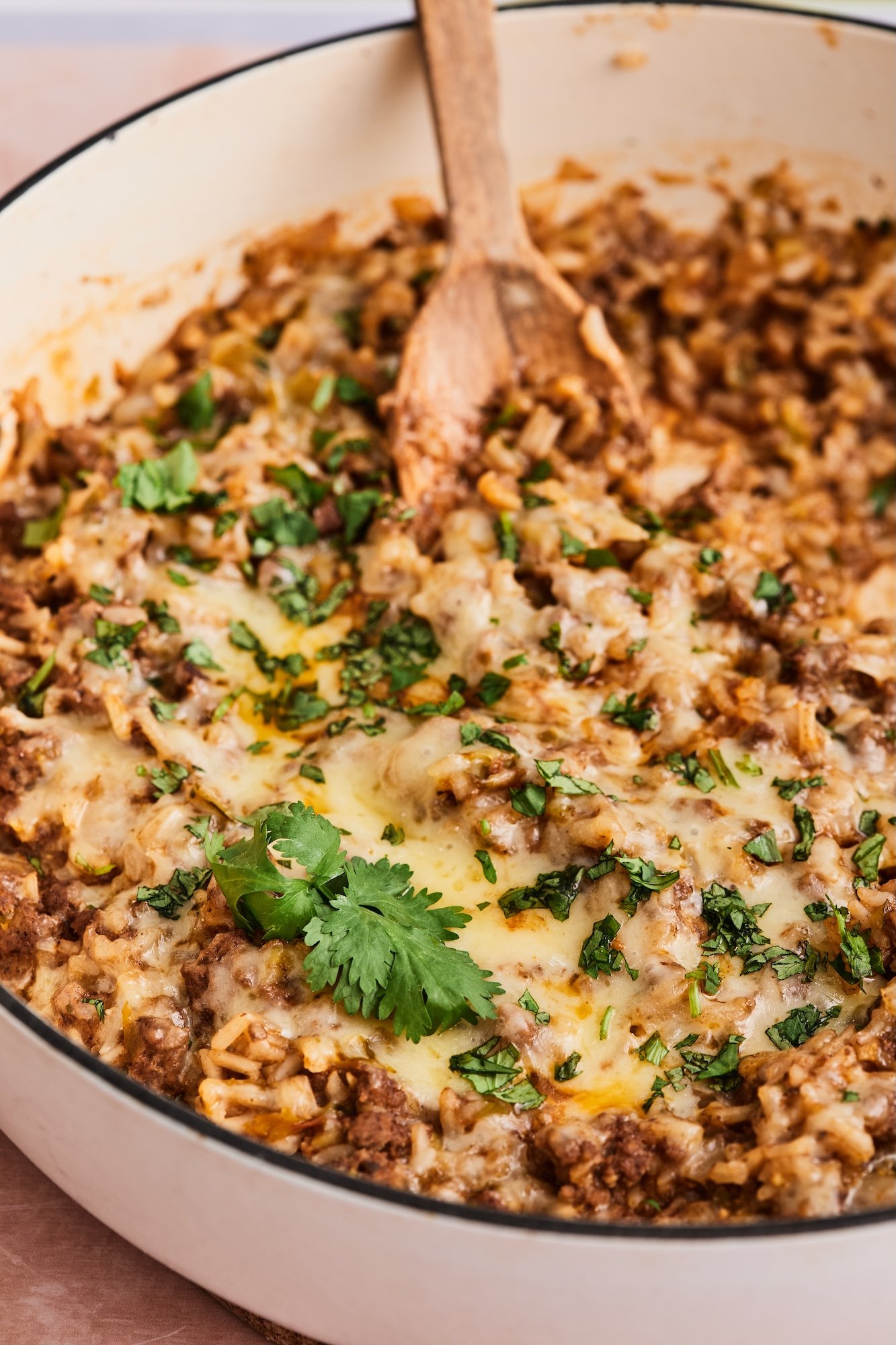 Close-up of ground beef and rice skillet garnished with fresh herbs.