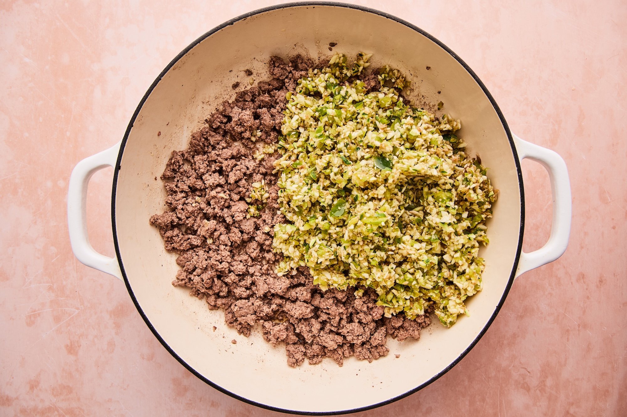 Vegetables and browned beef in skillet, ready to cook until softened.