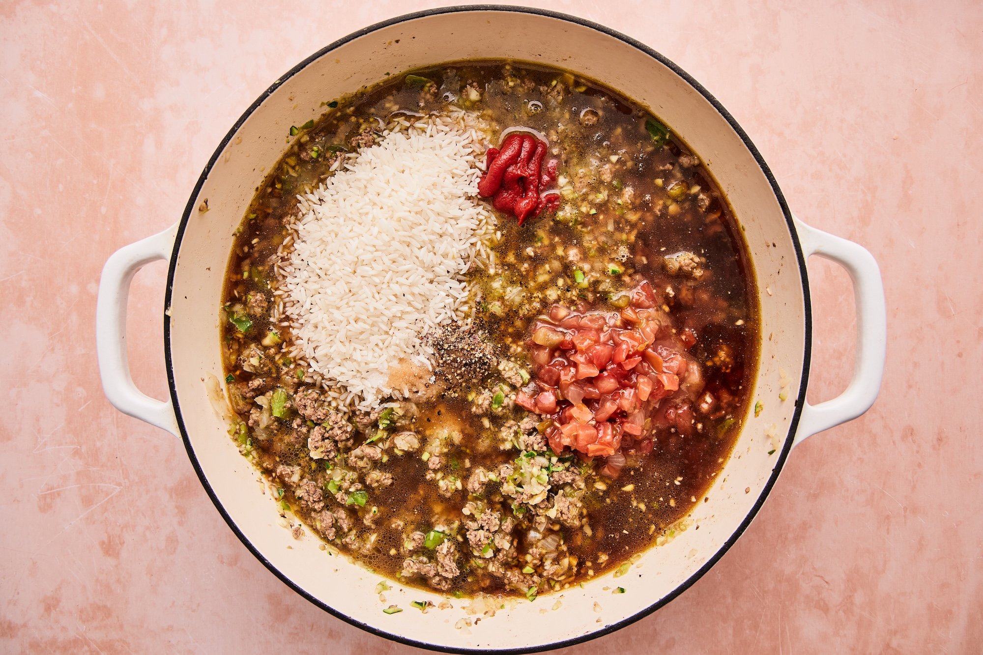 Broth, salsa, rice, tomato paste, salt, and pepper in the skillet with the chopped vegetables and browned beef.