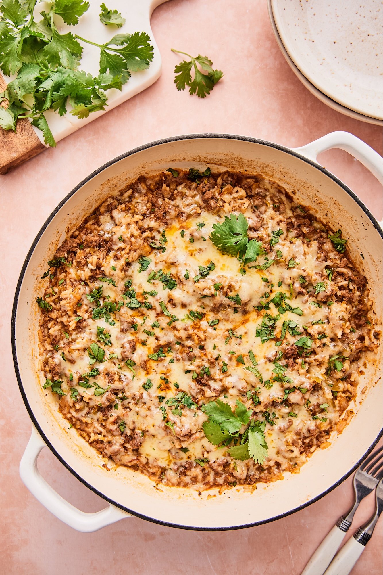 Ground beef and rice skillet in a large white skillet on a pink countertop.
