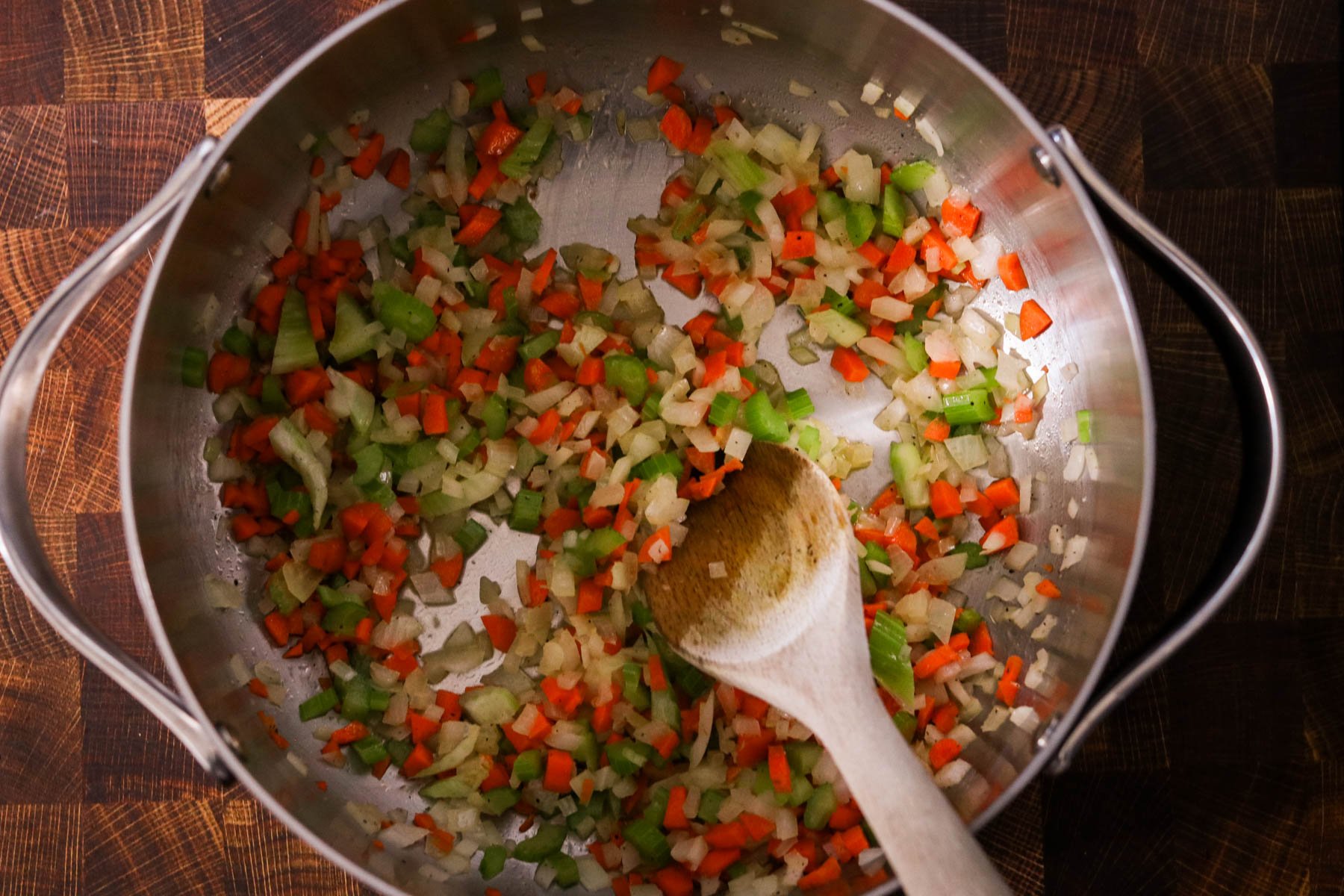 Onions, carrots, and celery sautéing in a large pot with butter, salt and pepper. 