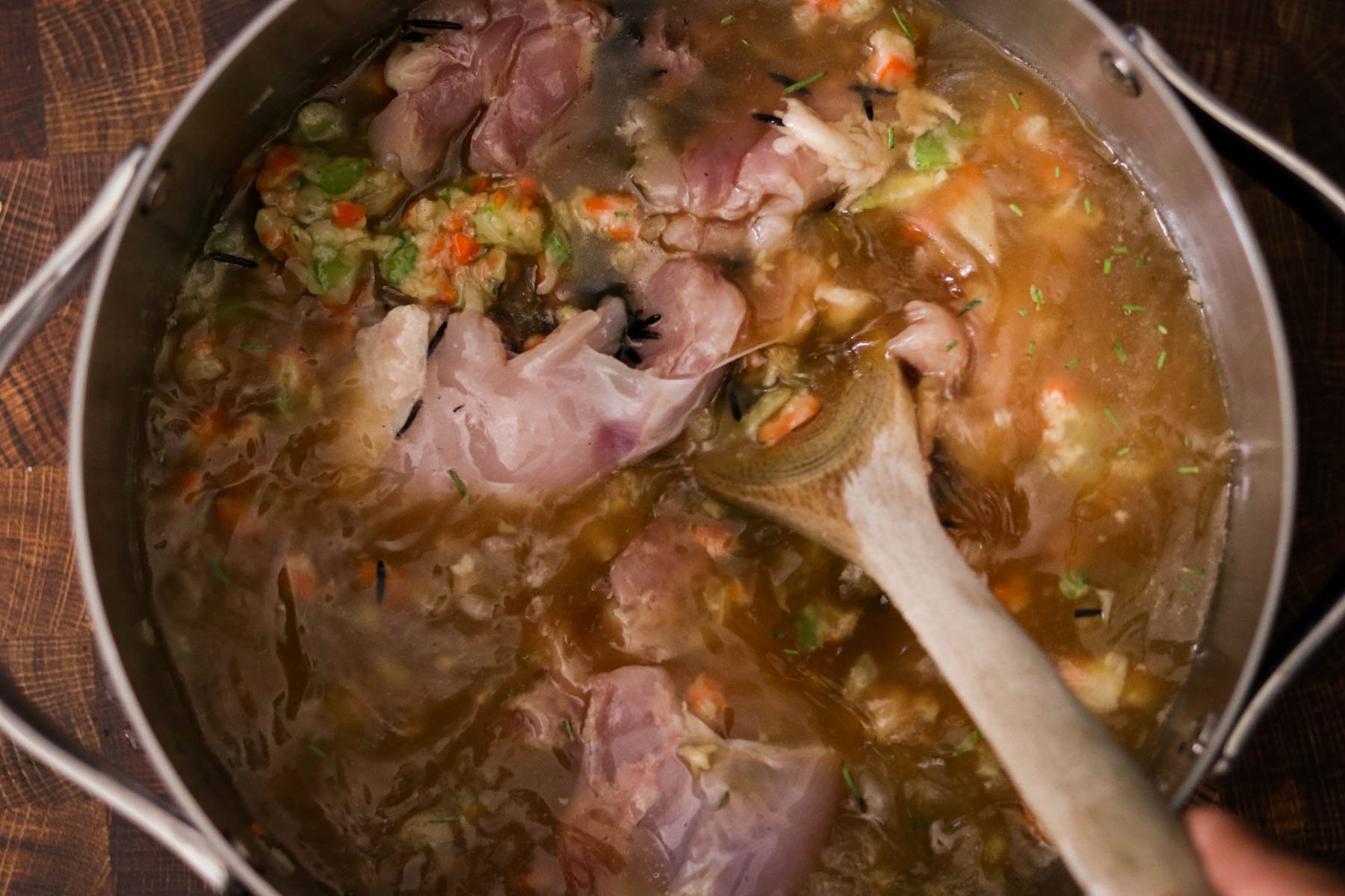 Chicken and wild rice soup cooking in large pot until rice is tender and the chicken is cooked.