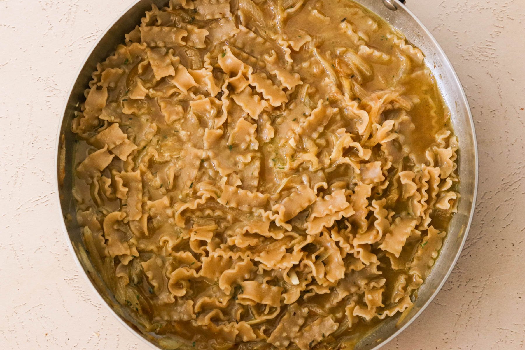 Short pasta simmering in beef broth with onions.