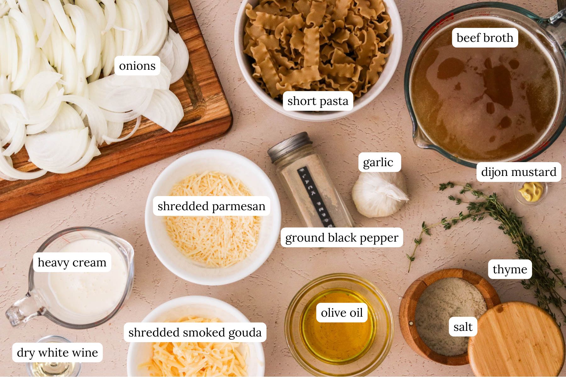 Overhead of ingredients for French onion pasta including, onions, garlic, thyme, wine, broth, pasta, cream, and cheeses.