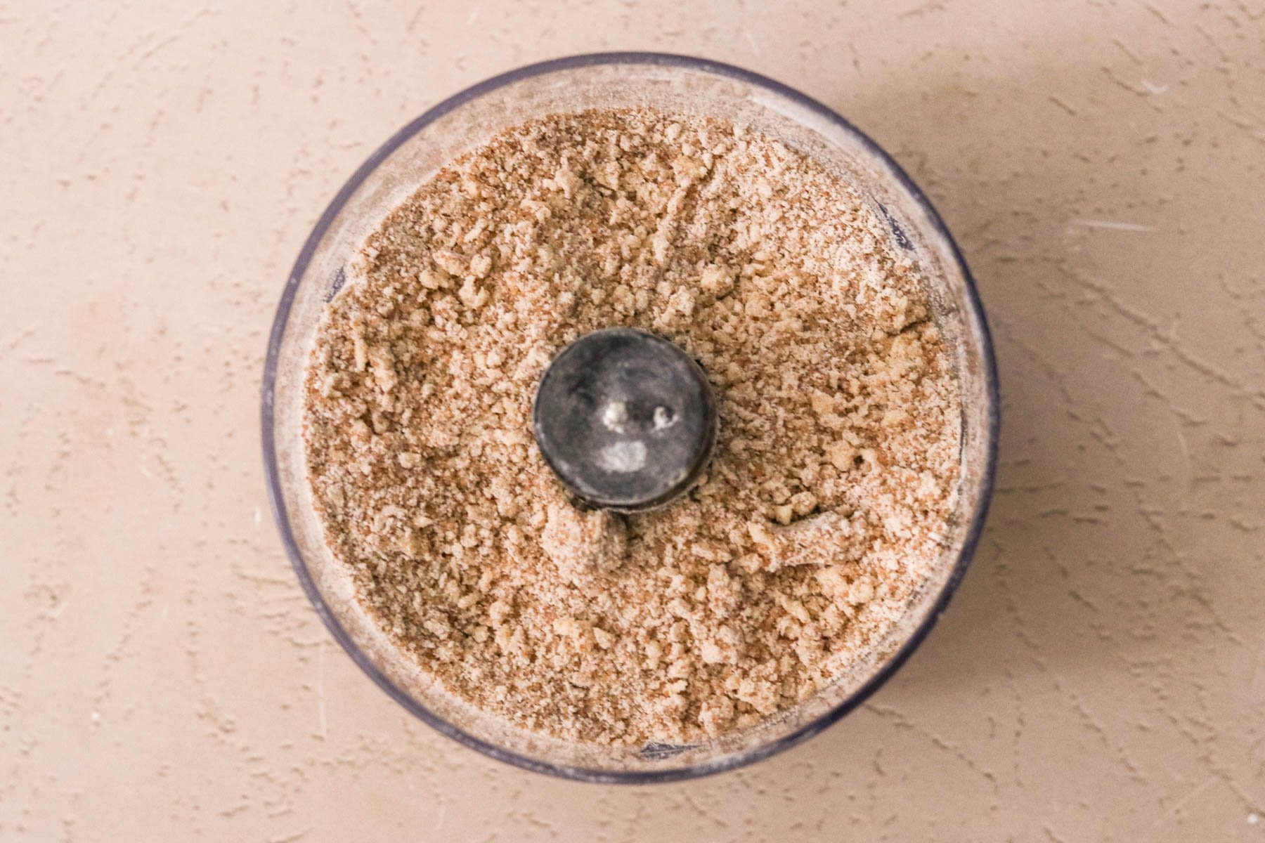 Food processor bowl with cinnamon brown sugar crumb topping mixture.