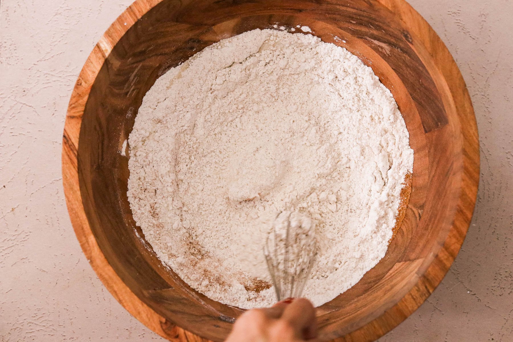Dry ingredients--gluten-free flour, sugar, pumpkin spice, leaveners--stirred in a wooden mixing bowl.