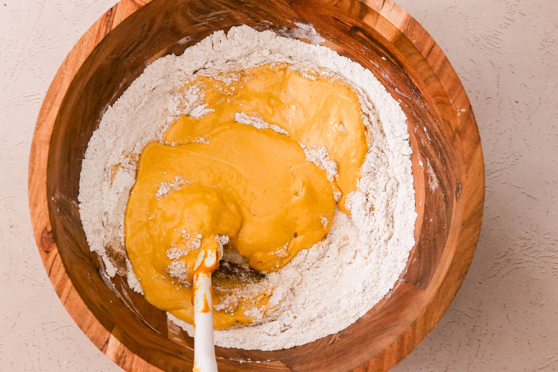 Wet ingredients poured into dry ingredients to make pumpkin coffee cake batter.