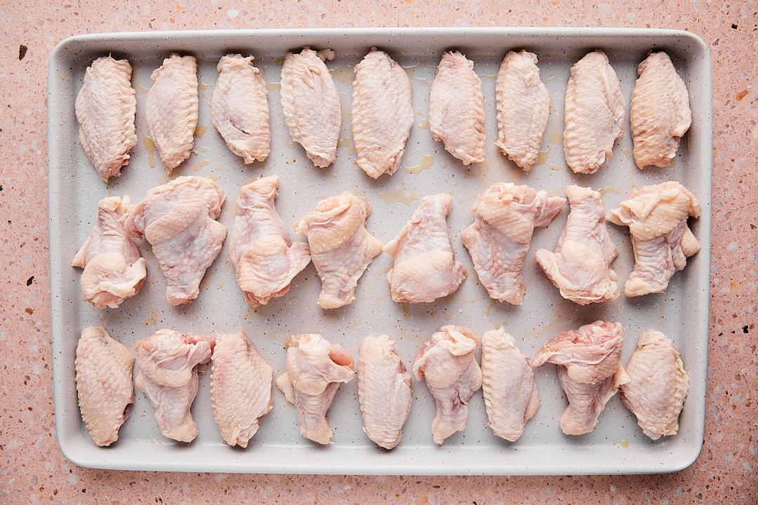 Chicken wings lined in a single layer on a baking sheet.