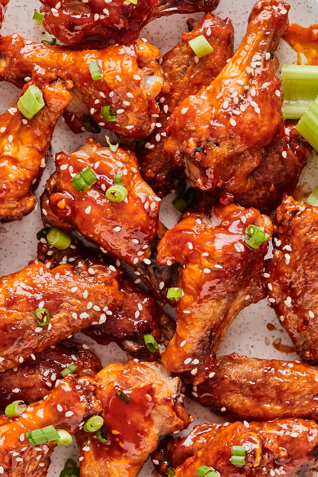 Close-up of plated baked honey sriracha wings garnished with green onions and sesame seeds.