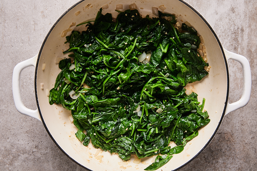 Fresh baby spinach, salt, and pepper, in Dutch oven with shallot and garlic.