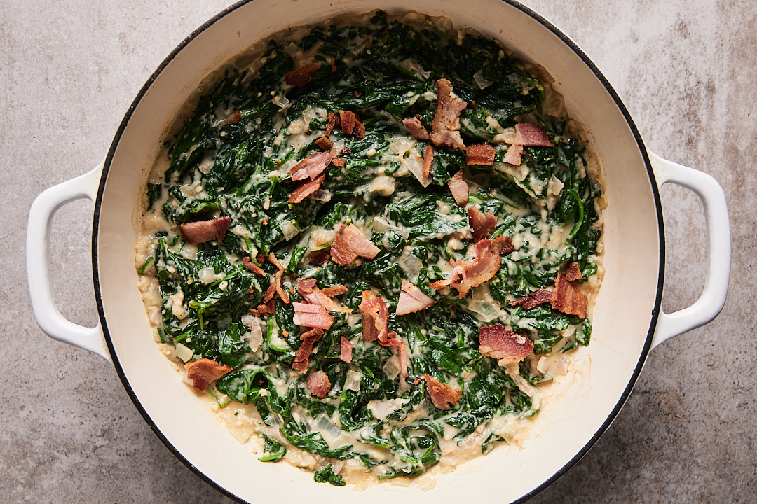 Keto creamed spinach in a Dutch oven topped with bacon bits.