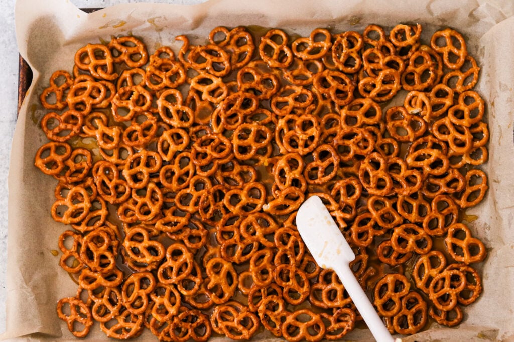 toffee getting poured over the pretzels on a baking sheet