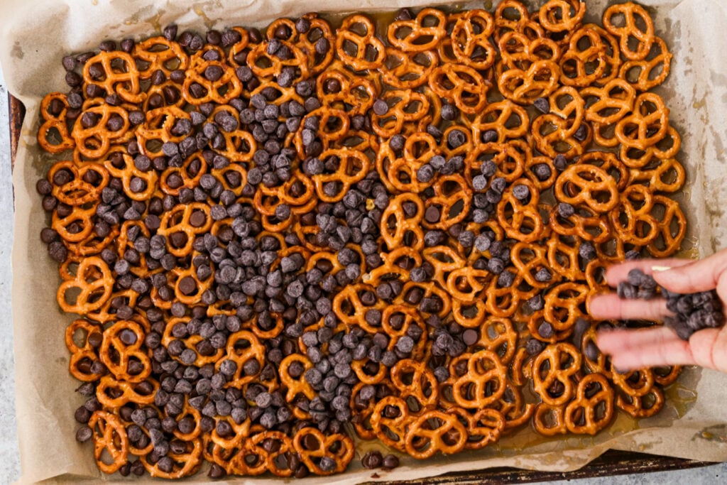 sprinkling chocolate chips atop the pretzels and toffee