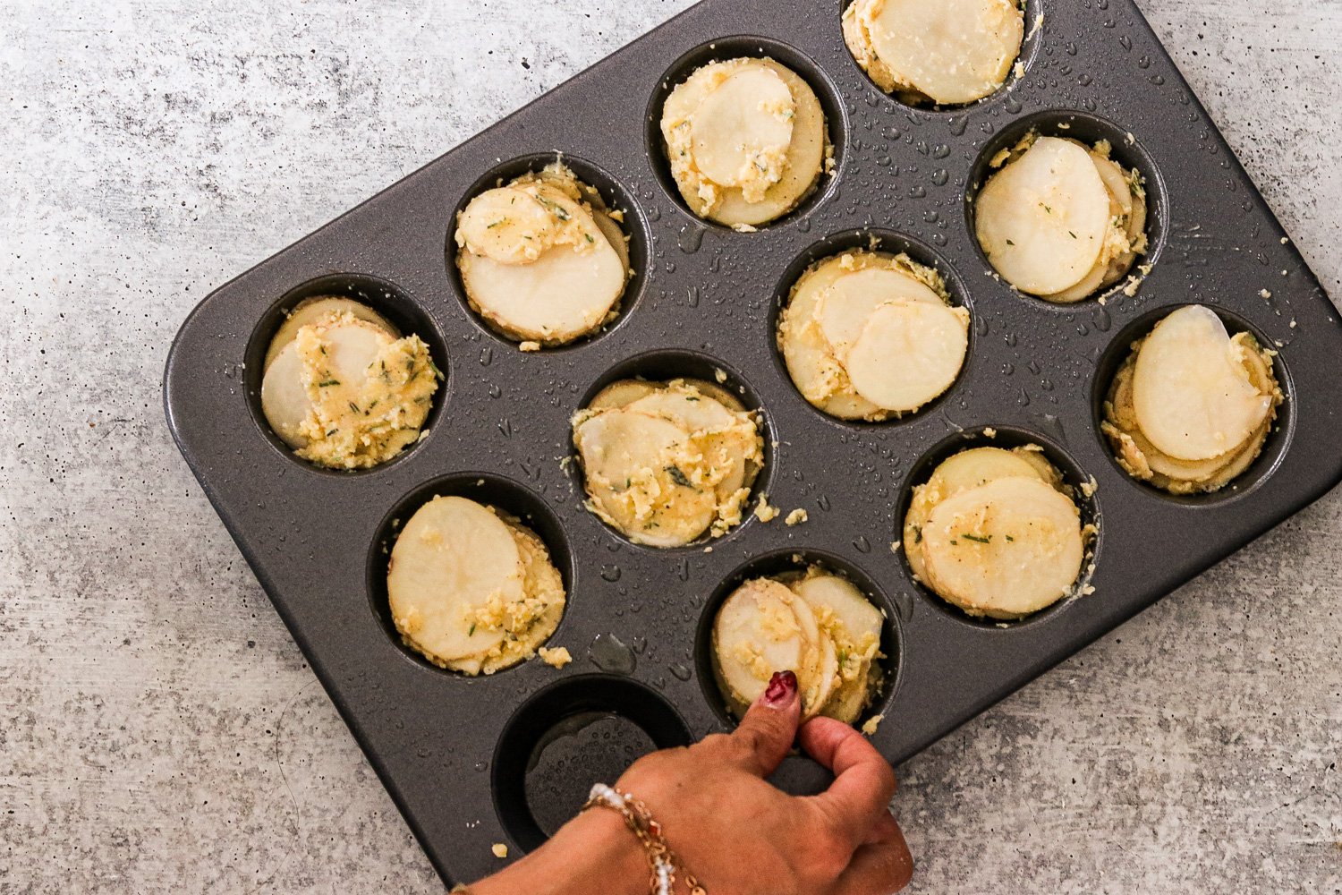 Potato slices stacked in a muffin tin, each cup filled to the top.