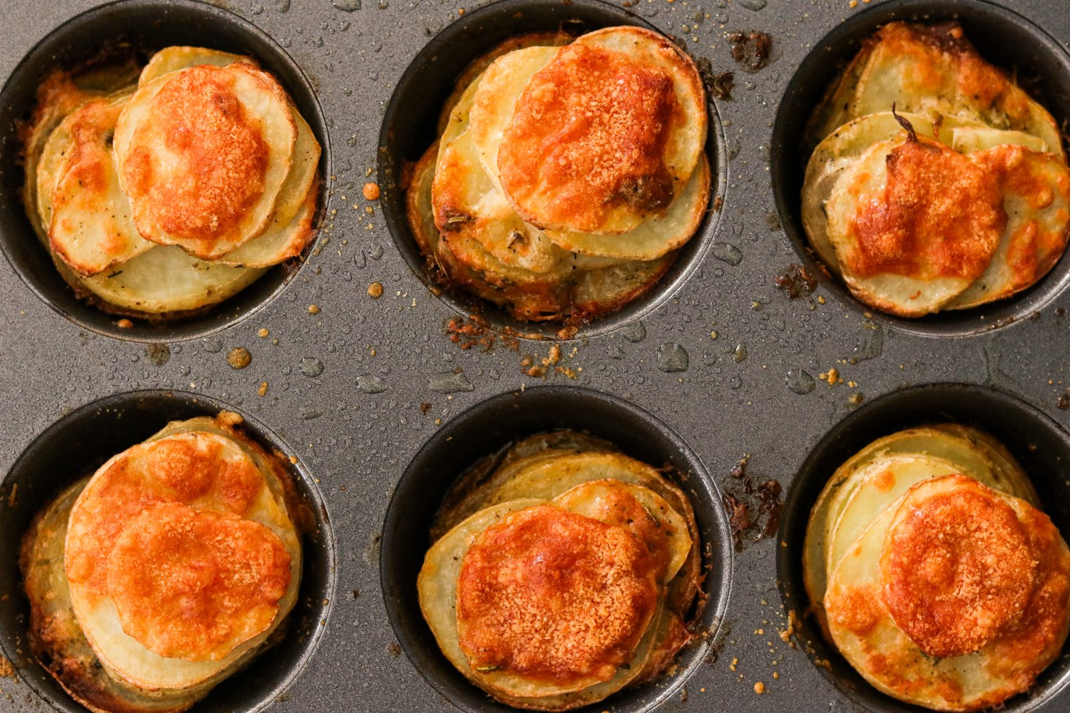 Freshly baked crispy stacked potatoes in a muffin tin.