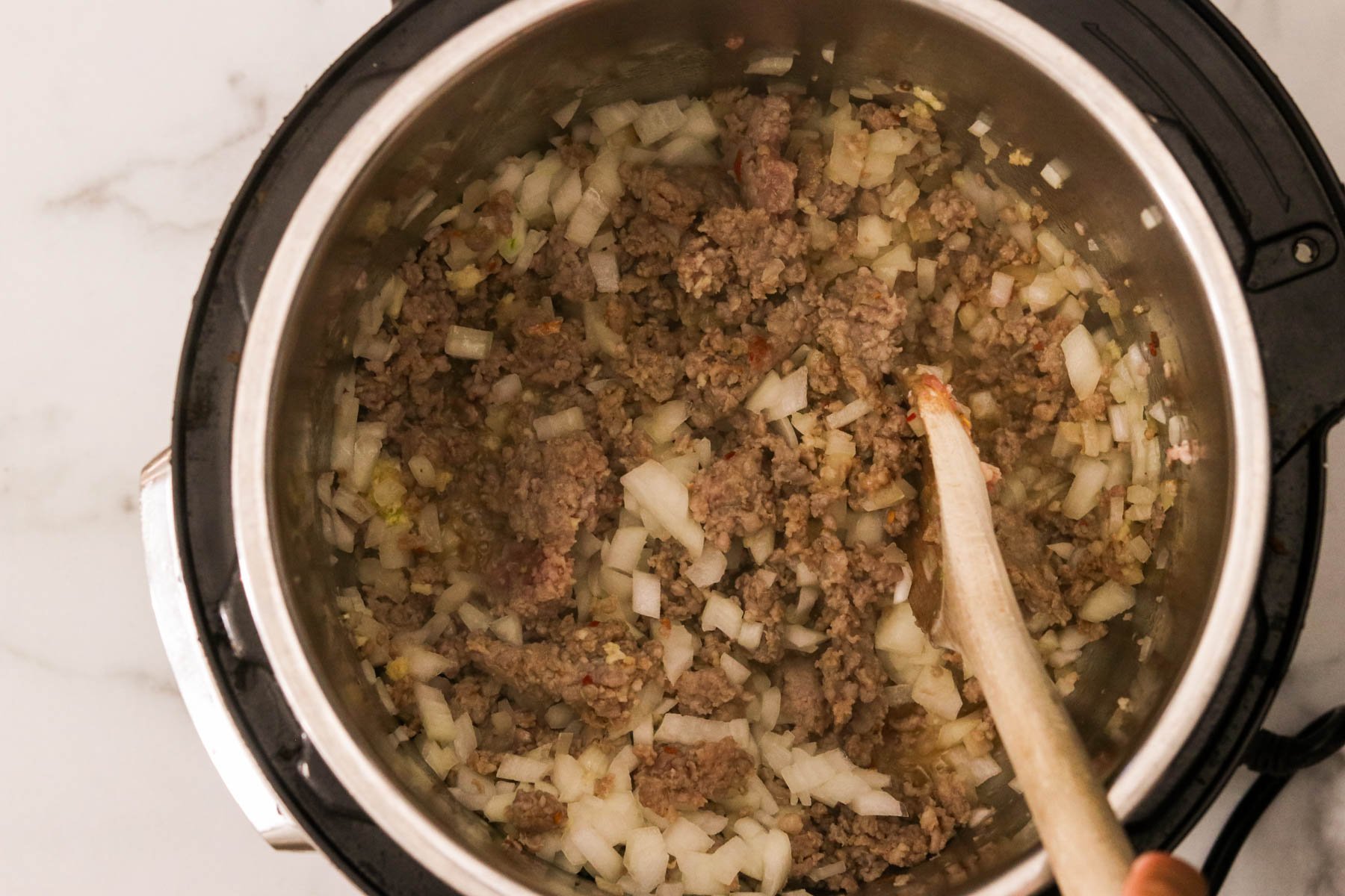 Instant Pot with Italian sausage, onion, and garlic.